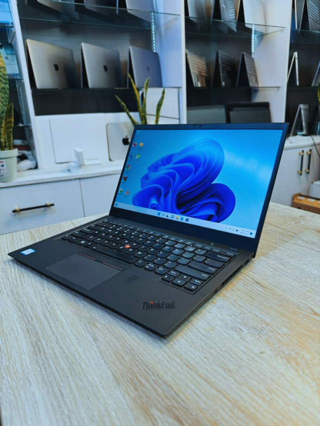 Lenovo ThinkPad laptop on a wooden desk with Windows 11 screen.