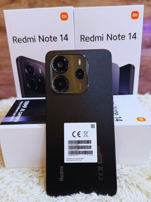 Redmi Note 14 5G smartphone in black color placed in front of its retail boxes, highlighting its dual-camera setup and sleek matte finish design.