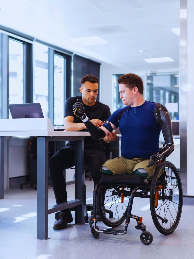 Man using advanced prosthetic arms in a wheelchair, assisted in a modern healthcare facility, symbolizing AI innovations in medicine.