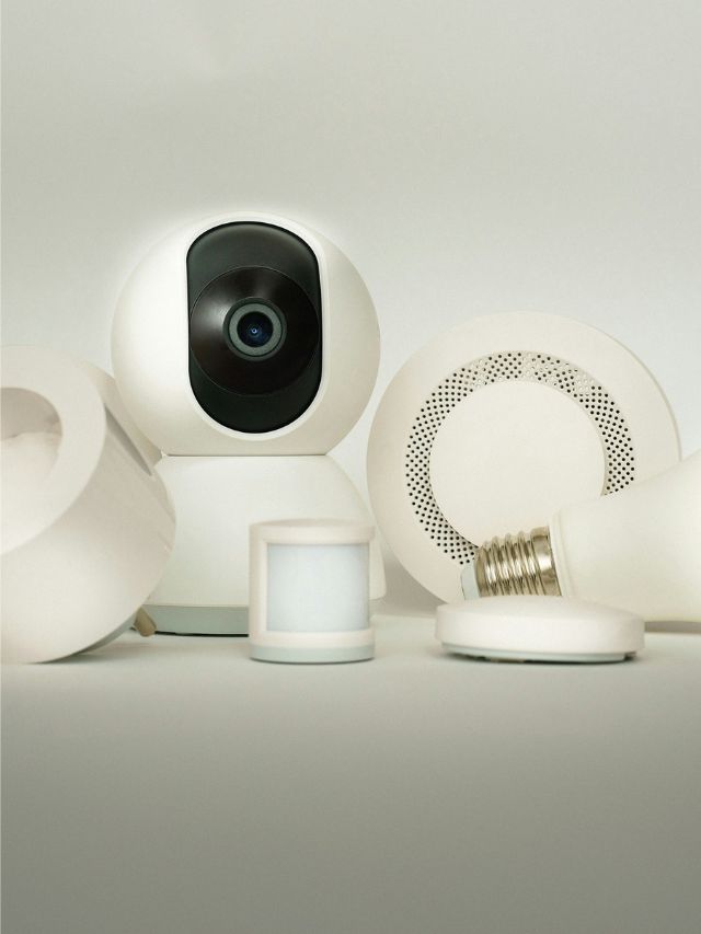 Collection of smart IoT home devices including security camera, smart plug, sensor, light bulb, and smart speaker.
